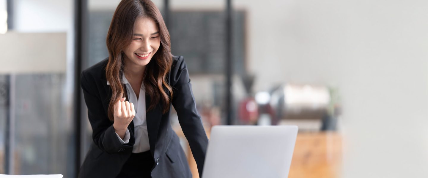 Beautiful asian woman using laptop computer, exciting and celebrating with good news of business successful. Small business startup concept.
