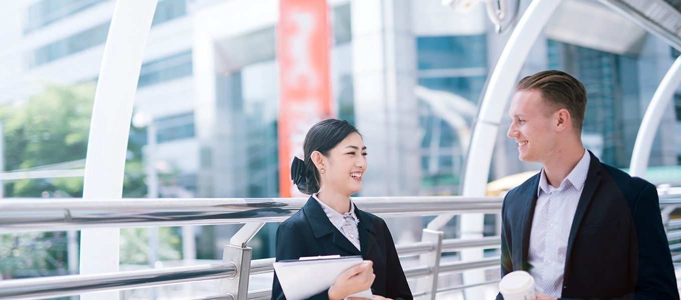 smiling-business-colleagues-talking-while-standing-bridge-city