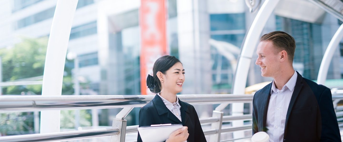 smiling-business-colleagues-talking-while-standing-bridge-city