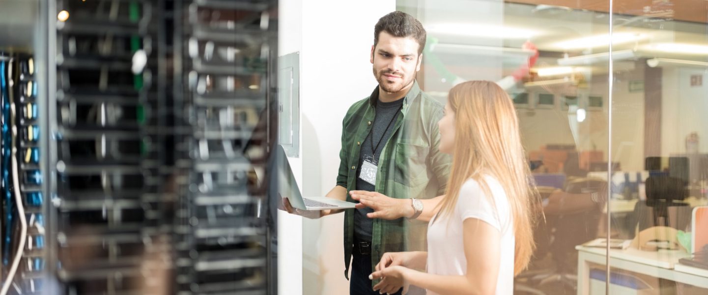 two-business-people-standing-server-room-with-laptop-discussing